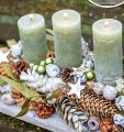 Natürliche Adventsdeko: Kerzen in Salbeigrün mit Zapfen auf hellem Holz