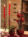 Rote Stabkerzen in goldenen Kerzenhaltern mit Beeren