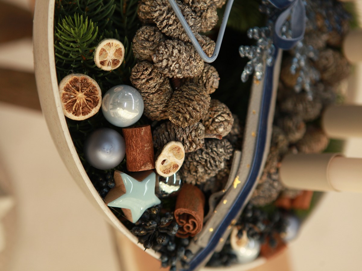 Adventsschale mit Zapfen, Zimtstangen, Orangenscheiben und blauen Mini-Weihnachtskugeln