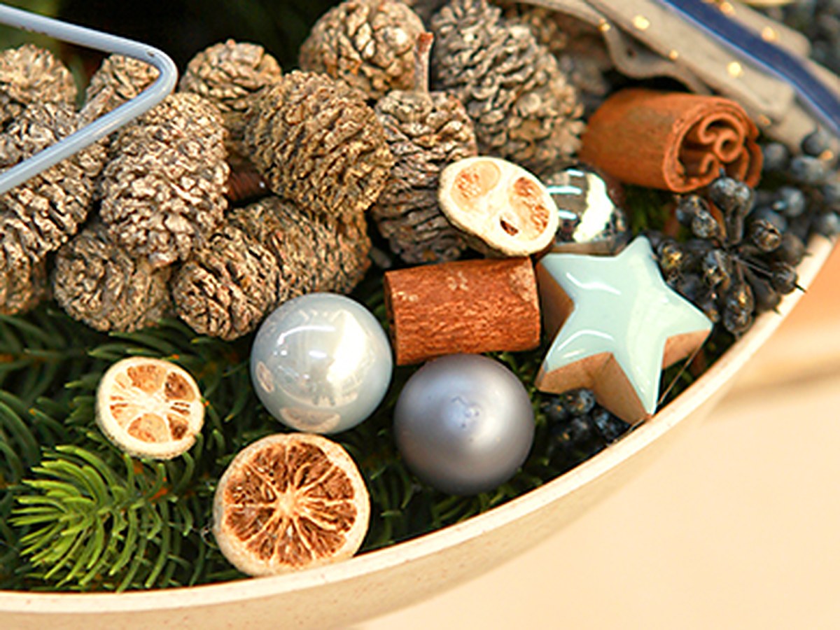 Adventsschale mit Zapfen, Zimtstangen, Orangenscheiben und blauen Mini-Weihnachtskugeln